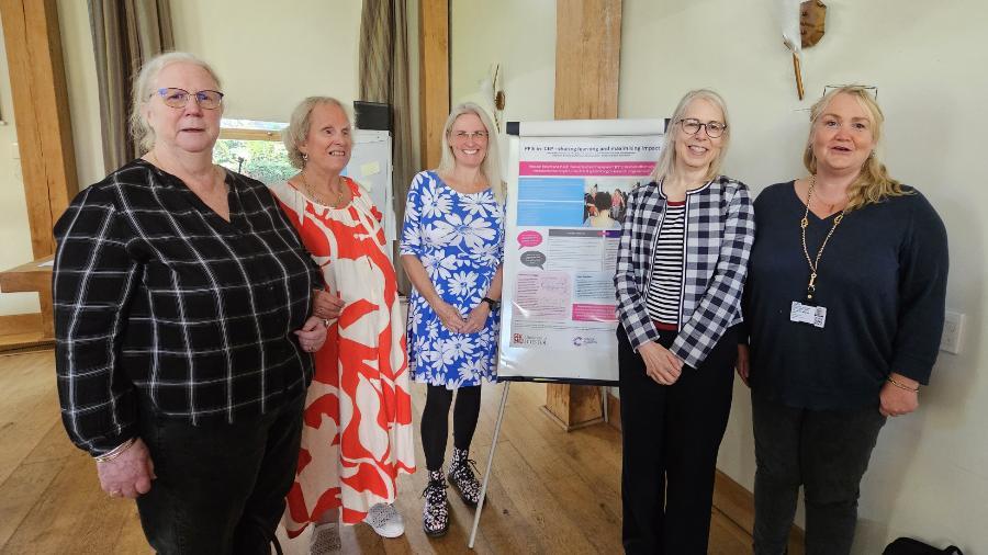 Five women in a line either side of a poster.